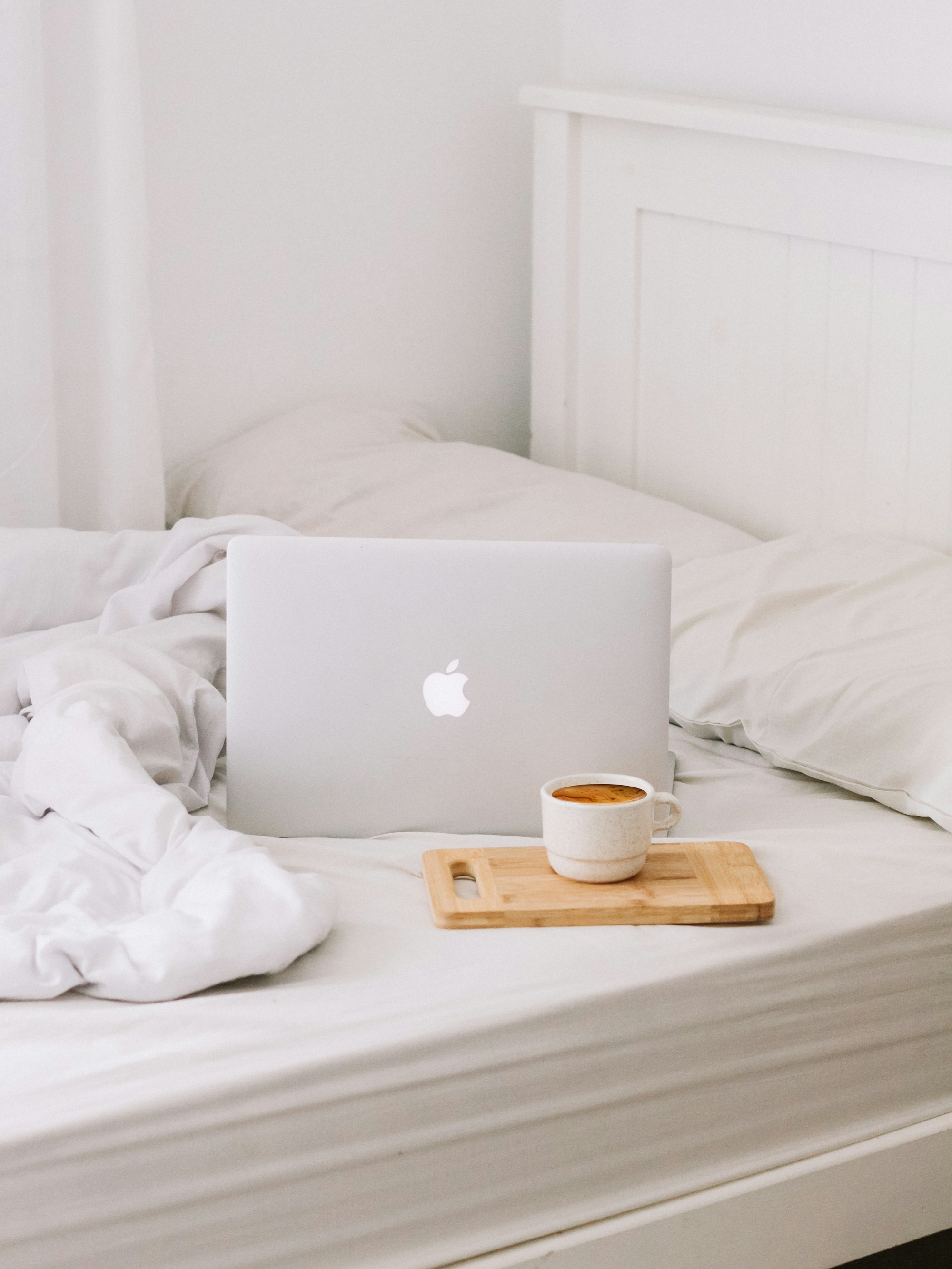 A laptop and cup of tea on a cosy bed, ready for an online session from home