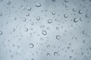 Raindrops on a window against a grey sky