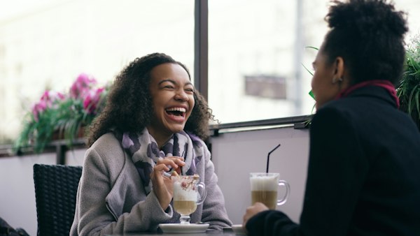 Two friends laughing together over coffee
